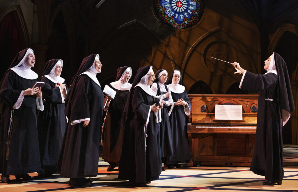 Billede fra 'Sister Act' på Det Ny Teater, hvor skuespilleren Julie Steincke som Deloris hjælper nonnerne med at finde deres stemme i en hjertevarm scene.