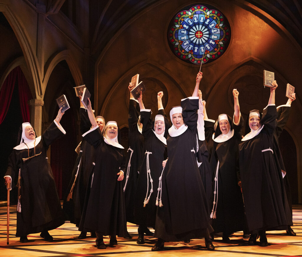 Billede fra 'Sister Act' på Det Ny Teater, hvor Nonnerne synger den livlige sang 'Syng Dig Fri' med glæde og energi.