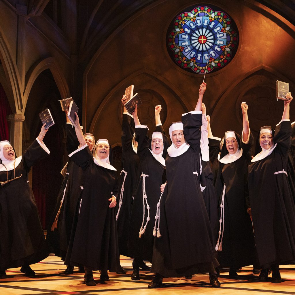 Billede fra 'Sister Act' på Det Ny Teater, hvor Nonnerne synger den livlige sang 'Syng Dig Fri' med glæde og energi.